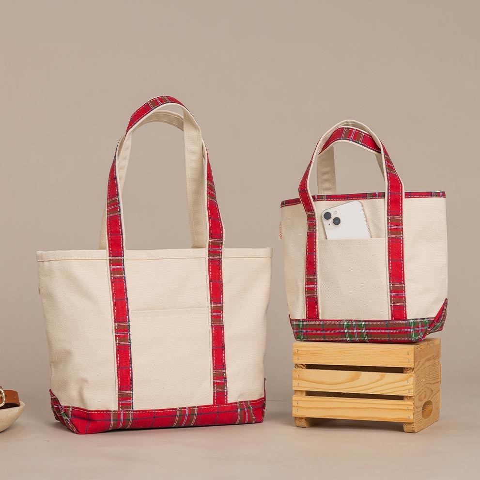 Brown waxed canvas duffel bag and toiletry pouch on a wooden table against a white brick wall