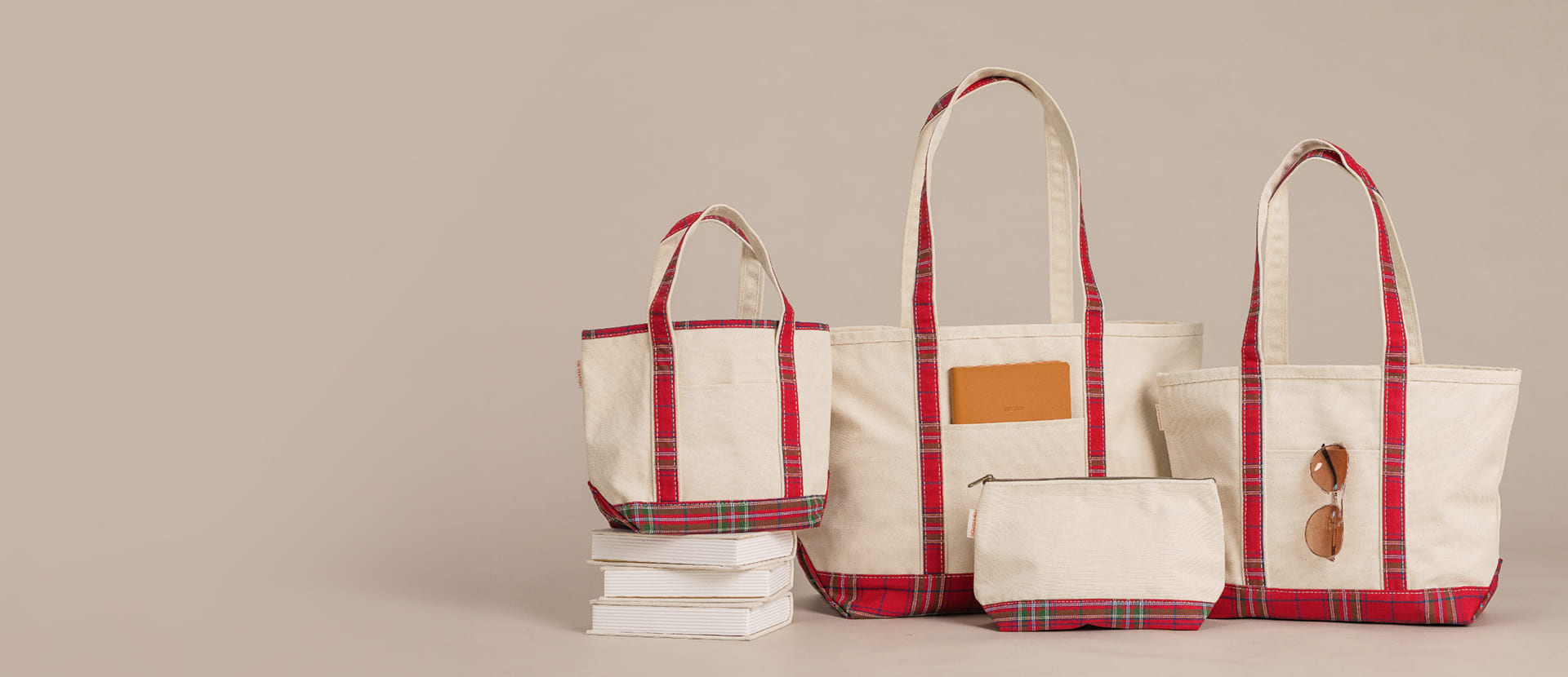 Brown waxed canvas duffel bag and toiletry pouch on a wooden table against a white brick wall