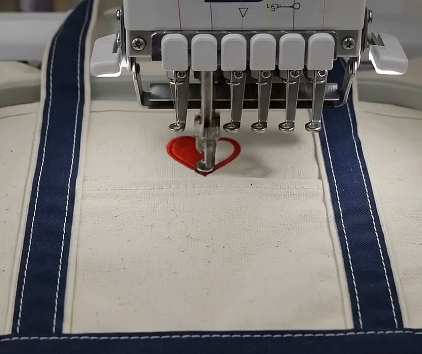 Industrial embroidery machine personalizing a canvas tote